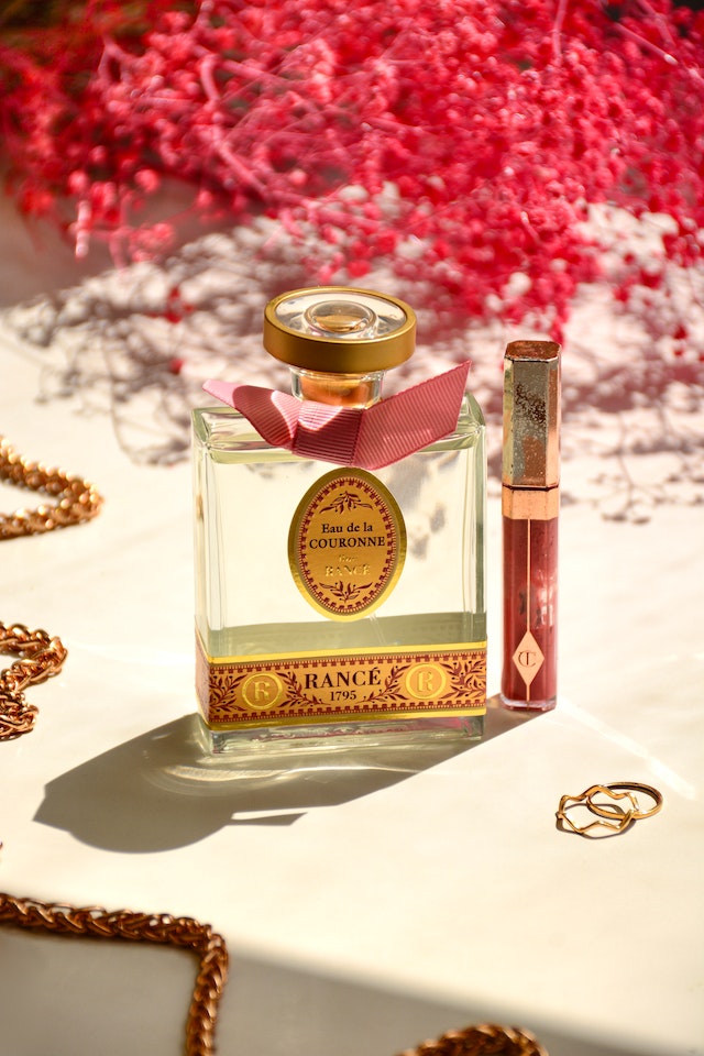 perfume bottle on table beside red flowers